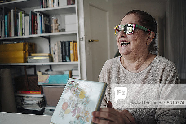 Glückliche ältere Frau mit kaputter Sonnenbrille zu Hause