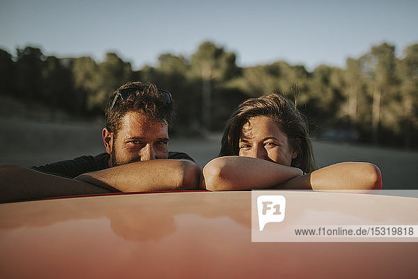 Glückliches Paar auf einer Autoreise  macht eine Pause  lehnt auf dem Autodach
