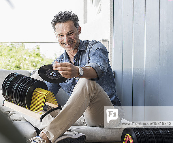 Mature man sitting at home looking at vintage sigle recors