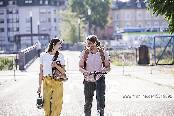Young couple with electric scooter walking on the street