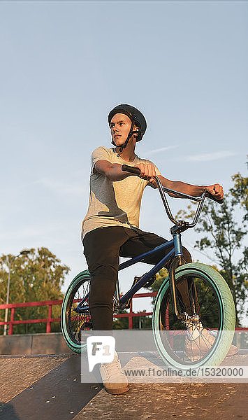 Young man with BMX bike at skatepark having a break