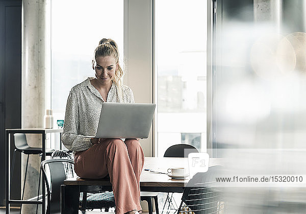 Geschäftsfrau sitzt im Büro mit Laptop am Tisch