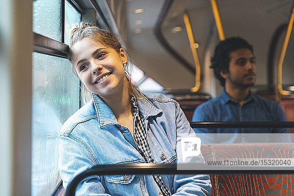 Porträt einer glücklichen jungen Frau  die mit dem Bus reist  London  UK