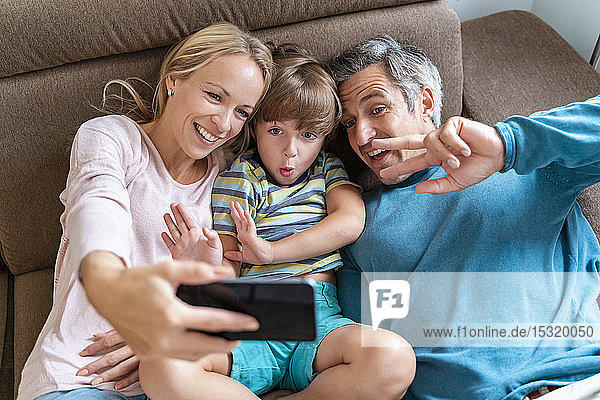 Vater  Mutter und Sohn nehmen sich zu Hause auf der Couch ein Selfie