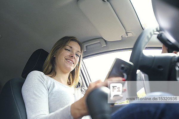 Young woman using smartphone in her car