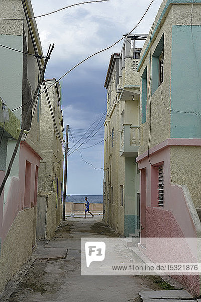 Kuba  Gibara  ein junger Mann läuft am Ende eines bunten Hauses vorbei