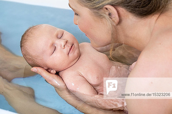 Moment der Zärtlichkeit einer jungen hübschen Mutter mit ihrem Baby in der Badewanne.