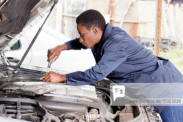 Eine Mechanikerin repariert den Motor eines Autos in ihrer Werkstatt.