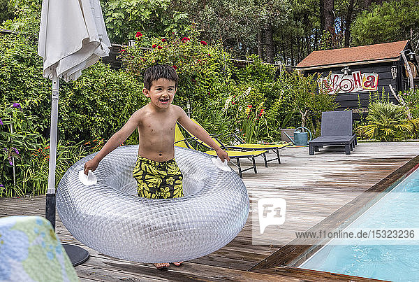 6-jähriger Junge spielt mit einem aufblasbaren Schwimmkörper auf dem Pooldeck