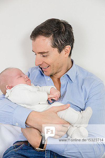 Junger zärtlicher Vater  der sein 2 Monate altes Baby im Arm hält.