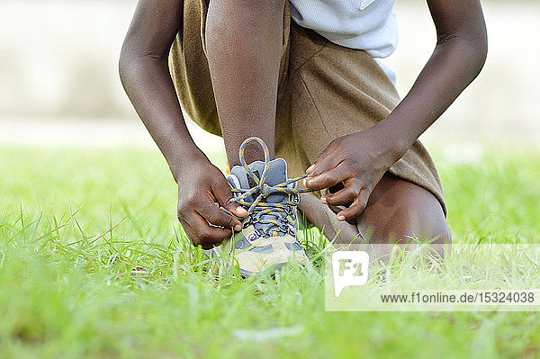 Ein Kind Knie  binden seine Schuhe Lanzen  besser zu laufen.