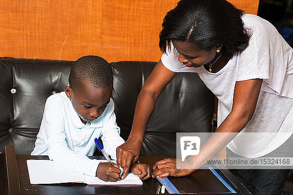 Mom shows her child where he has to write in his notebook.