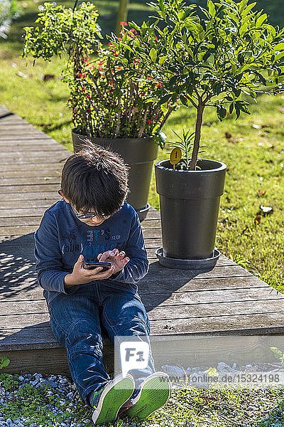 Siebenjähriger Junge spielt mit einem Mobiltelefon