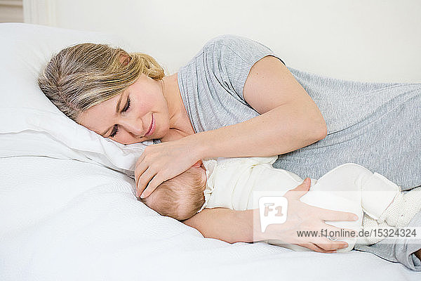 Porträt einer schönen jungen lächelnden Mutter  die ihrem Baby die Brust gibt.