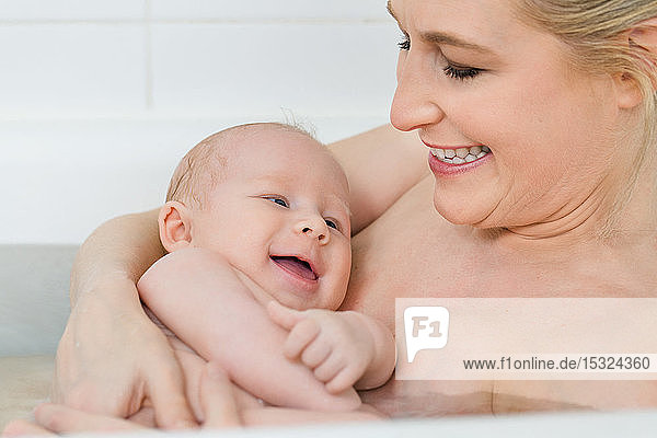 Moment der Zärtlichkeit einer jungen hübschen Mutter mit ihrem Baby in der Badewanne.
