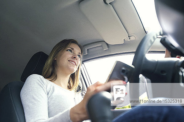 Junge Frau benutzt Smartphone in ihrem Auto