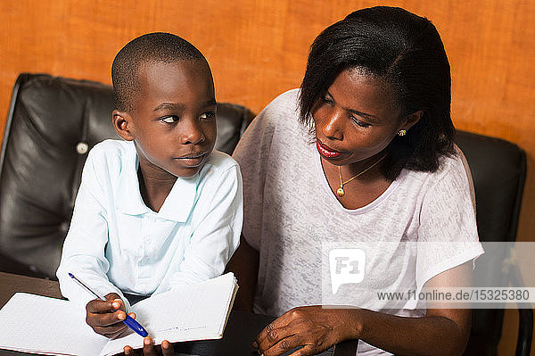 the child shows something to her mom in his notebook.