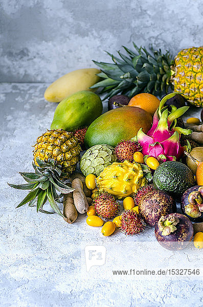 Ein großer Haufen verschiedener frischer und schmackhafter tropischer Früchte auf einem grauen Hintergrund