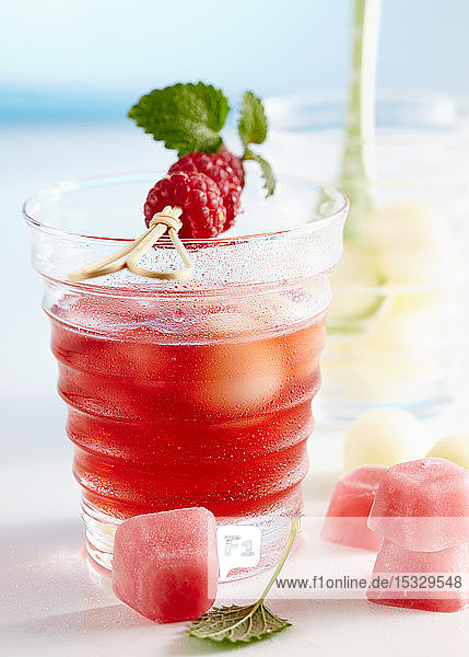 Alkoholfreie Bowle mit Himbeeren und Honigtaumelone  serviert mit rosa Eiswürfeln