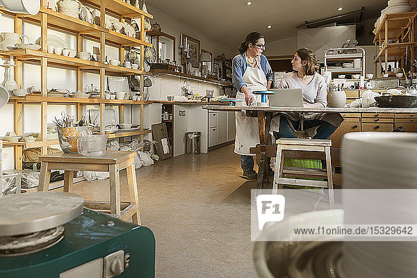 Women using laptop in pottery workshop