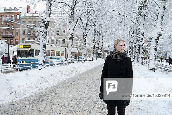 Junge Frau steht auf einer verschneiten Straße