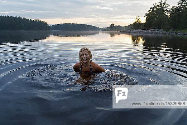 Woman in Lake Skiren at sunset in Sweden