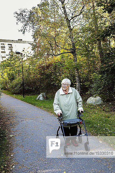 Senior woman using walking frame walking in park