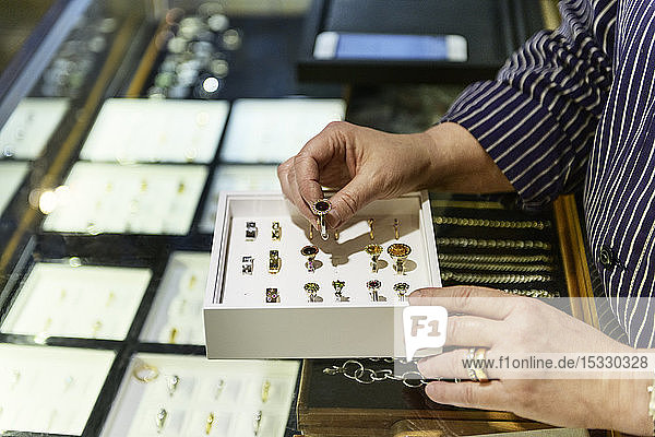 Hands of goldsmith examining box of rings