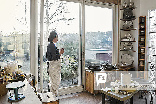 Woman by window in pottery workshop