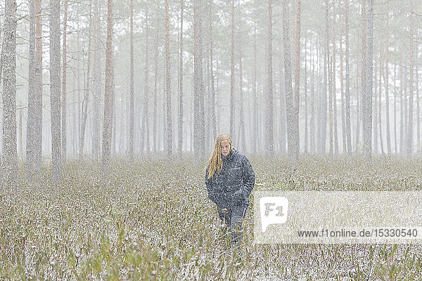 Junge Frau geht durch einen verschneiten Wald
