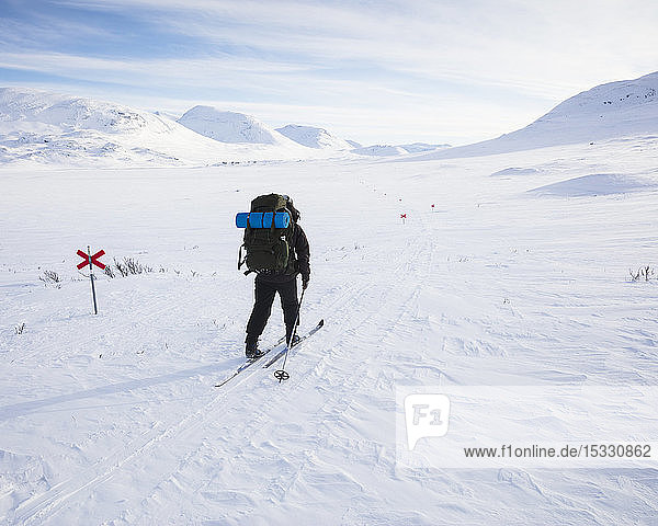 Frau beim Skifahren mit Markierungen auf der Kungsleden-Loipe in Lappland,  Schweden