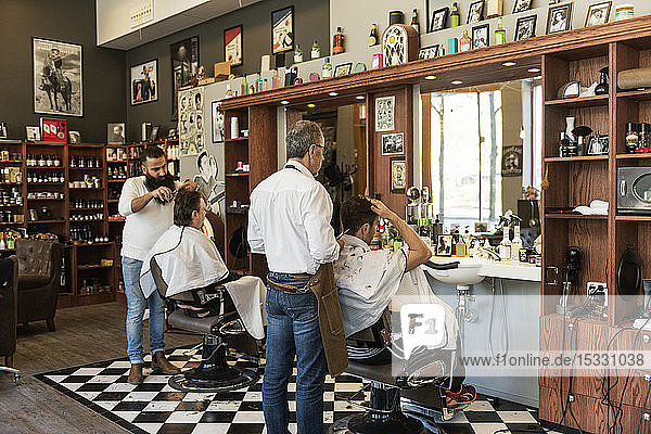 Barbers cutting customer´s hair