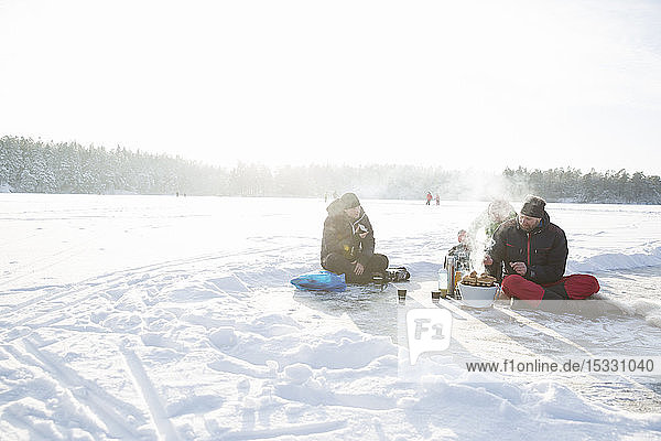 Junge und Männer mit Grill auf dem zugefrorenen Drang-See in Uppland,  Schweden