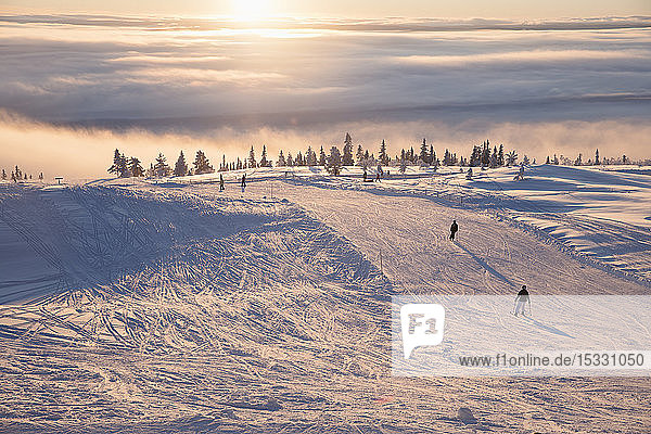 Menschen beim Skifahren bei Sonnenuntergang