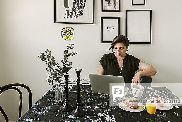 Young woman using laptop during breakfast