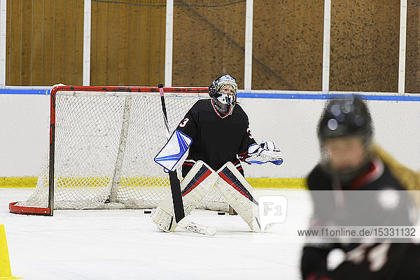 Girl in goalkeeper uniform during ice hockey training