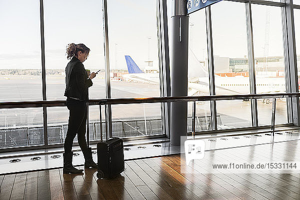 Woman with suitcase and smart phone in airport