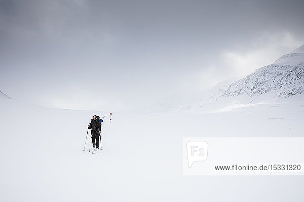 Frau beim Skifahren in den Bergen auf dem Kungsleden in Lappland,  Schweden