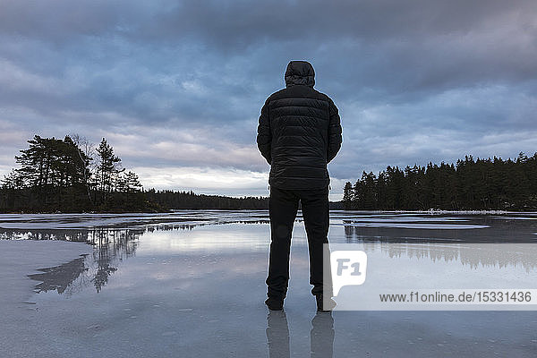 Mann steht auf gefrorenem See