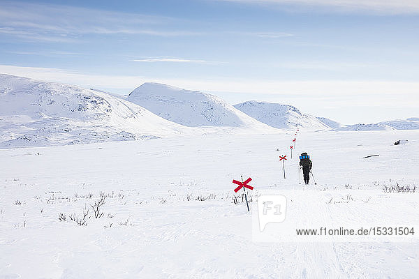 Frau beim Skifahren mit Markierungen auf der Kungsleden-Loipe in Lappland,  Schweden