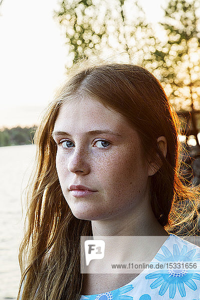 Portrait of young woman with lake in background