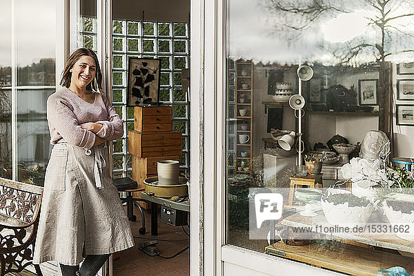 Woman leaning on door of pottery workshop
