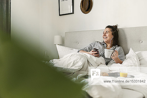 Young woman using smart phone in bed