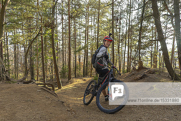 Mid adult man leaning on mountain bike in a forest
