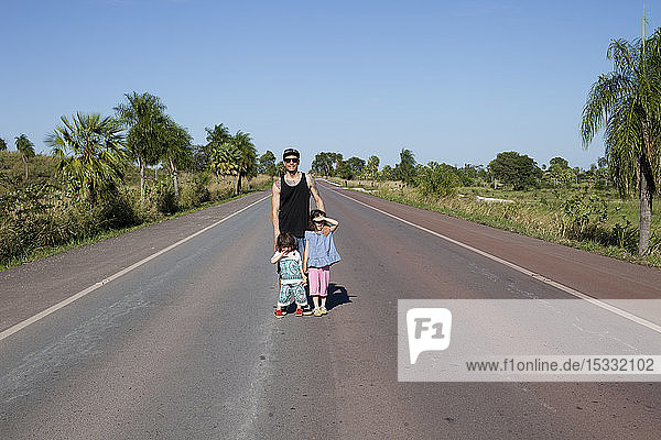 Mid adult man and children standing on rural road in the Pantanal Wetlands Brazil