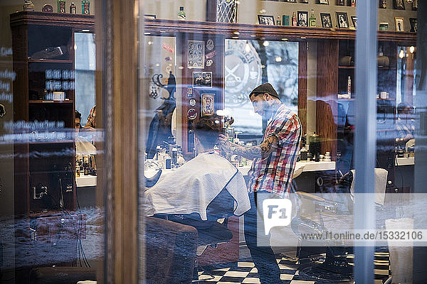 View through window of barber cutting customer´s hair