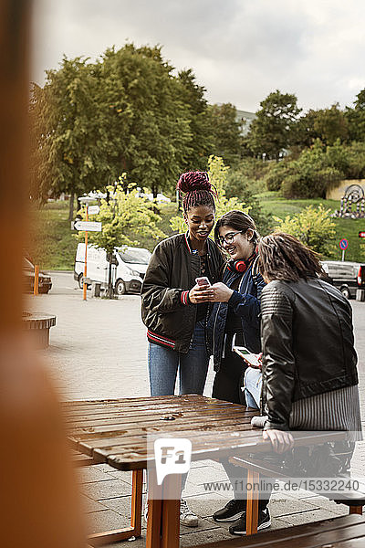 Teenage girls using smart phone in park