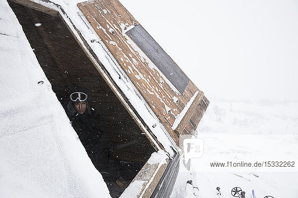 Man in roof of log cabin with snow