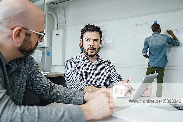 Männer benutzen ein digitales Tablet während einer Besprechung im Büro