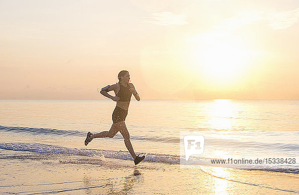 Woman jogging on beach at sunset